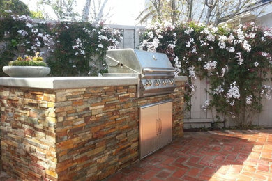 This is an example of a medium sized traditional back patio in Orange County with an outdoor kitchen, brick paving and no cover.
