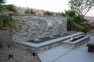Diseño de patio tropical de tamaño medio sin cubierta en patio trasero con fuente y losas de hormigón