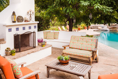 Ejemplo de patio mediterráneo de tamaño medio sin cubierta en patio trasero con adoquines de piedra natural y chimenea