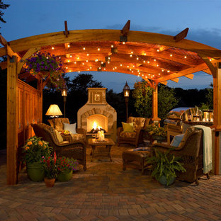Example of a classic concrete paver patio design in Milwaukee with a gazebo and a fireplace