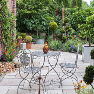 This is an example of a medium sized traditional side patio in Berkshire with a water feature, concrete paving and no cover.