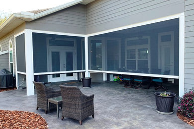 Cette photo montre une terrasse arrière chic de taille moyenne avec une dalle de béton et une extension de toiture.