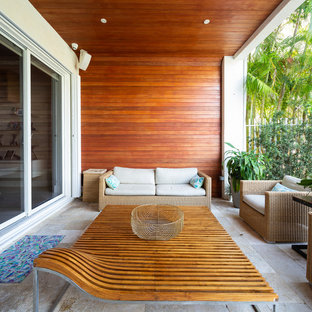Ispirazione per un patio o portico tropicale con pavimentazioni in pietra naturale e un tetto a sbalzo
