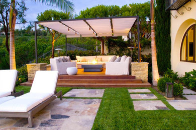 Cette photo montre une grande terrasse arrière tendance avec un foyer extérieur, des pavés en pierre naturelle et un gazebo ou pavillon.