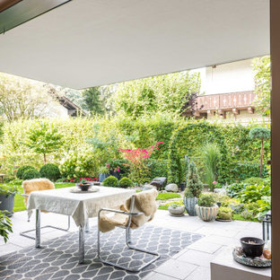 Überdachter Moderner Patio neben dem Haus mit Kübelpflanzen und Natursteinplatten in München