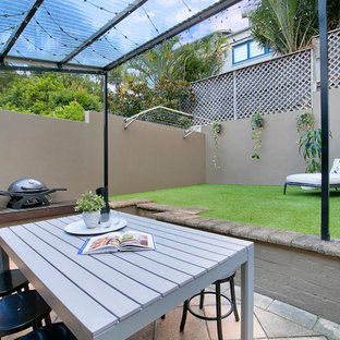This is an example of a transitional backyard patio in Sydney with natural stone pavers.