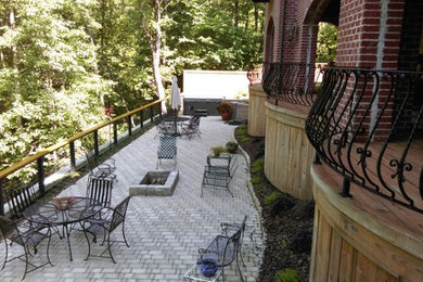 This is an example of a large traditional back patio in Birmingham with brick paving and no cover.