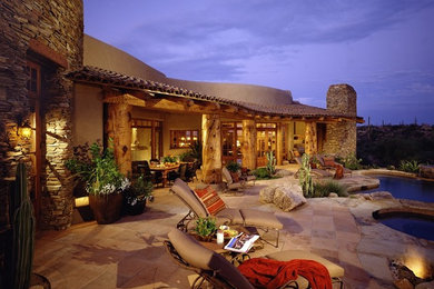 フェニックスにある広いサンタフェスタイルのおしゃれな裏庭のテラス (天然石敷き、張り出し屋根) の写真