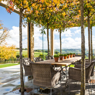 Idee per un grande patio o portico country con una pergola e pavimentazioni in pietra naturale