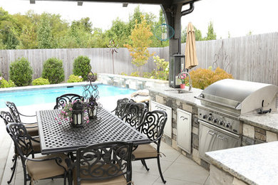 Modelo de patio clásico renovado grande en patio trasero con cocina exterior, suelo de baldosas y cenador