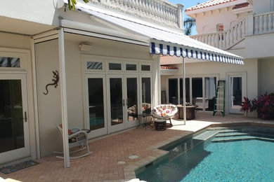 Large world-inspired back patio in Tampa with brick paving and an awning.