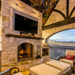 Ispirazione per un grande patio o portico stile rurale dietro casa con un caminetto, piastrelle e un tetto a sbalzo