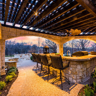 Immagine di un grande patio o portico stile rurale dietro casa con pavimentazioni in pietra naturale e una pergola