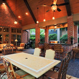 Immagine di un patio o portico stile americano dietro casa con cemento stampato e un tetto a sbalzo