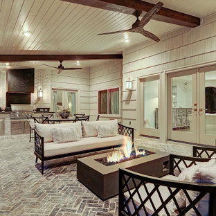 Immagine di un patio o portico chic di medie dimensioni e dietro casa con pavimentazioni in mattoni e un tetto a sbalzo