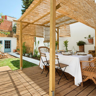 Esempio di un patio o portico mediterraneo di medie dimensioni e dietro casa con un giardino in vaso, pedane e un parasole