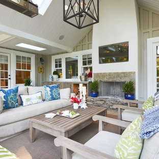 Immagine di un patio o portico stile marinaro con un tetto a sbalzo e un caminetto