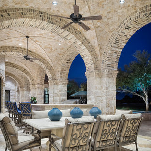 Example of a huge tuscan backyard patio design in Austin with a fire pit and a roof extension