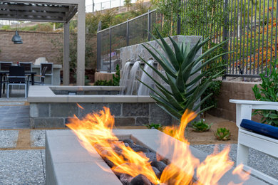 Inspiration for a large contemporary back patio in Orange County with a fire feature, natural stone paving and a pergola.