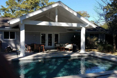 Example of a large transitional backyard concrete patio design in Houston with a roof extension