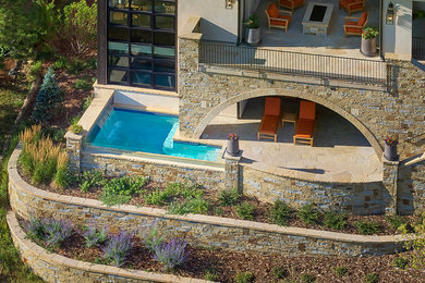 Inspiration for a large contemporary backyard stone patio fountain remodel in Denver with a roof extension