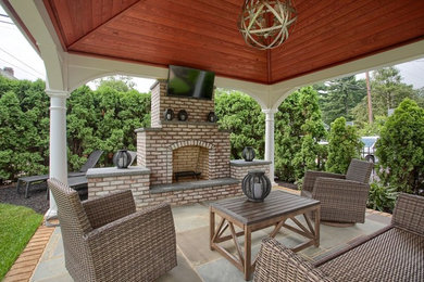 Medium sized classic back patio in Philadelphia with a fire feature, natural stone paving and a gazebo.
