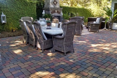 Large rustic back patio in Miami with a fire feature and brick paving.
