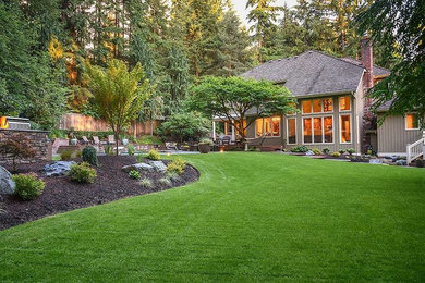 This is an example of a large traditional back patio in Seattle with a fire feature and natural stone paving.