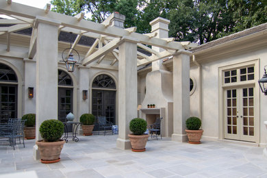 Patio - large french country courtyard stone patio idea in Denver with a fireplace and a pergola