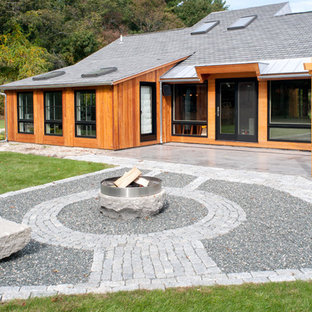 Immagine di un patio o portico minimal di medie dimensioni e dietro casa con un focolare, ghiaia e una pergola