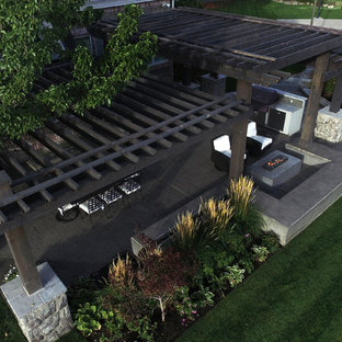 Esempio di un patio o portico minimal di medie dimensioni e dietro casa con cemento stampato e una pergola