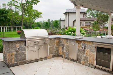 Large minimalist backyard concrete paver patio kitchen photo in New York with a pergola