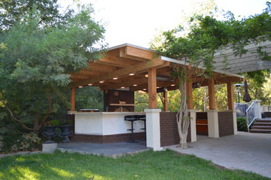 Inspiration for a large transitional backyard stone patio kitchen remodel in San Francisco with a pergola