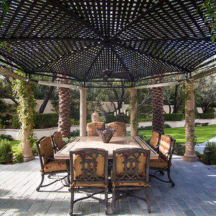 Foto di un grande patio o portico mediterraneo dietro casa con un focolare e un gazebo o capanno