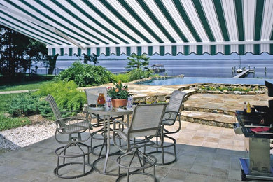 Idee per un patio o portico costiero di medie dimensioni e dietro casa con pavimentazioni in cemento e un parasole