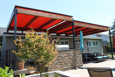 Imagen de patio minimalista de tamaño medio en patio trasero con cocina exterior, losas de hormigón y pérgola