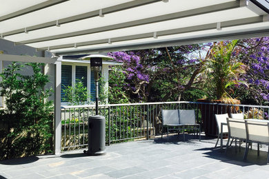Réalisation d'une grande terrasse minimaliste avec un point d'eau, une cour, une dalle de béton et une extension de toiture.