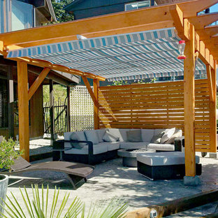 Ispirazione per un patio o portico stile americano dietro casa con un focolare, pavimentazioni in cemento e una pergola