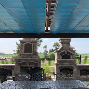 Immagine di un patio o portico american style dietro casa con un caminetto, pavimentazioni in pietra naturale e una pergola
