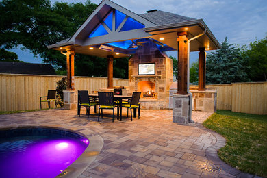 Modelo de patio clásico grande en patio trasero con cocina exterior, adoquines de hormigón y pérgola