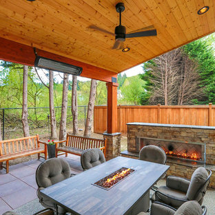 Immagine di un patio o portico stile americano di medie dimensioni e dietro casa con un caminetto, pavimentazioni in cemento e un tetto a sbalzo