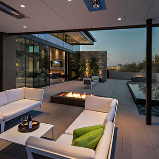 Foto di un grande patio o portico contemporaneo dietro casa con un focolare, un tetto a sbalzo e lastre di cemento