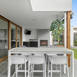 Large contemporary backyard patio in Geelong with with fireplace, tile and a roof extension.