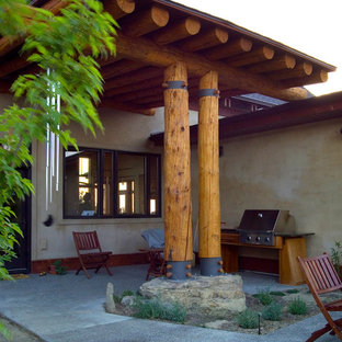 Immagine di un patio o portico etnico di medie dimensioni e in cortile con lastre di cemento e un parasole