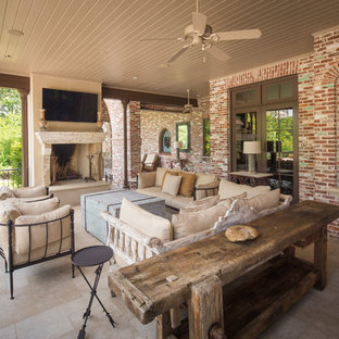 Example of a classic backyard stone patio design in Houston with a roof extension and a fireplace