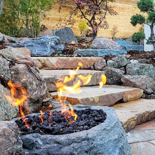 Immagine di un grande patio o portico etnico dietro casa con un focolare e pavimentazioni in pietra naturale