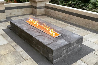 Photo of a large contemporary back patio in Detroit with a fire feature, tiled flooring and no cover.