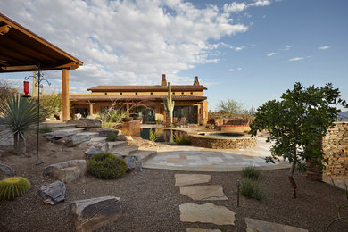 Patio - huge southwestern backyard stone patio idea in Phoenix with a roof extension