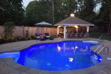 Modelo de piscina clásica grande en patio trasero con adoquines de piedra natural