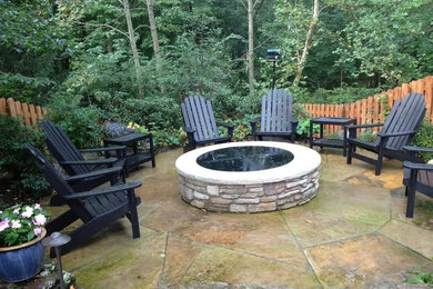 Example of a mid-sized minimalist backyard stone patio design in Other with a fire pit and no cover